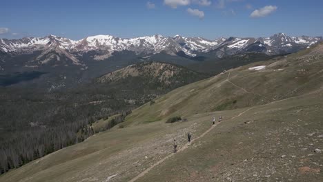 aerial orbits tourists on summit plateau ridge trail in rocky mtns
