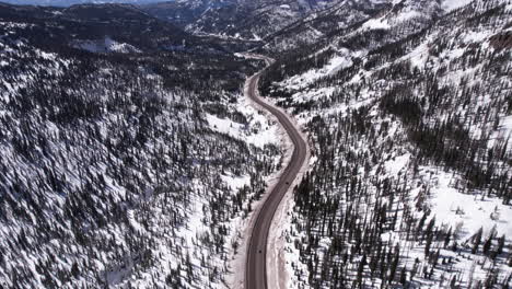 Drone-Shot-of-Traffic-on-Mountain-Pass-in-Colorado-USA-on-Sunny-Winter-Day,-Revealing-Snow-Capped-Peaks