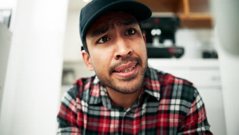 man in plaid shirt with cap using pliers