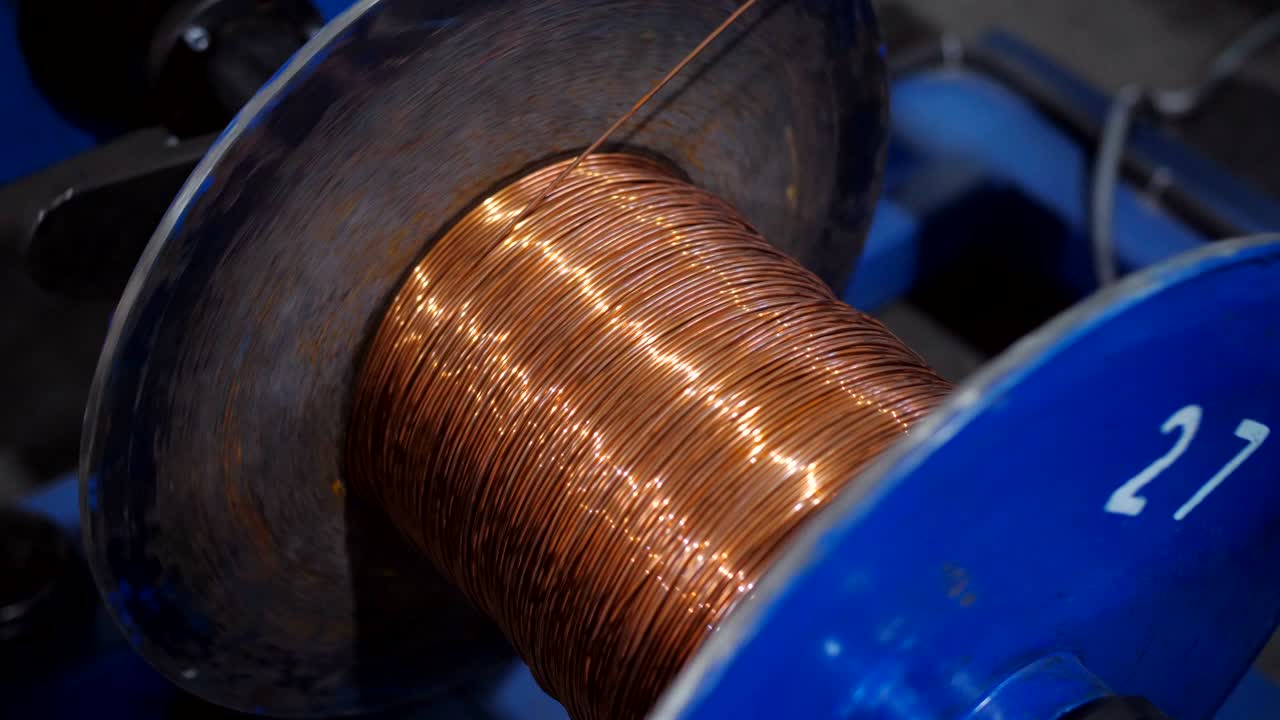 Copper wire unwinding from a spool. Closeup