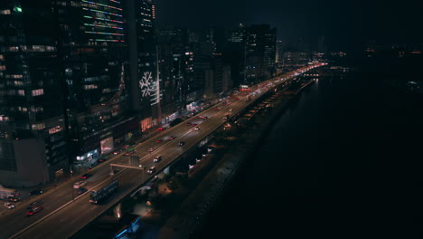 Approaching-sideways-shot-of-highway-with-traffic-and-illuminated-buildings-near-Kwun-Tong-Promenade,-Hong-Kong