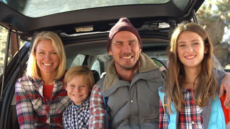 family sitting in open trunk of car, close up handheld shot