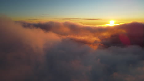 Flying-above-the-clouds-revealing-the-epic-view-of-the-mountain-summit-of-Mount-Rainier-volcano-at-sunset,-beauty-in-nature