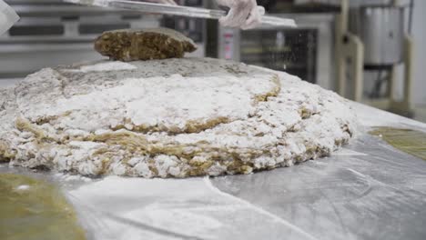 toma panorámica en cámara lenta de una masa de masa para dulces en una fábrica de dulces en medina sidonia mientras un panadero con una tableta de metal apila más masa