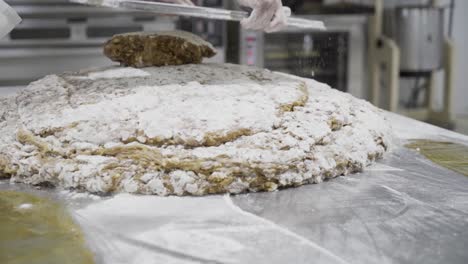 slow motion panning shot of a dough mass for sweets in a candy factory in medina sidonia while a baker with a metal tablet stacks more mass