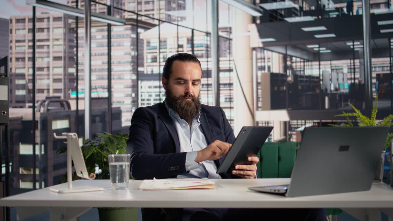 Imprenditore che controlla documenti con i dati aziendali e i KPI su tablet