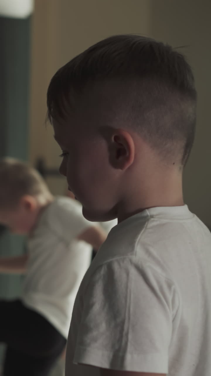 el niño golpea una bolsa colgante enorme en el gimnasio deportivo. el niño pequeño entrena golpeando equipos pesados en la escuela de artes marciales en cámara lenta.