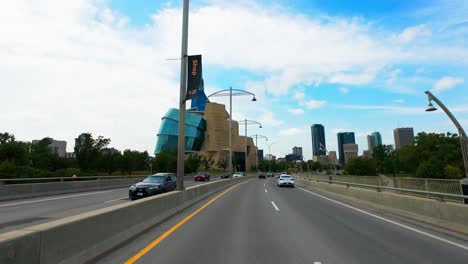 driving across provencher bridge with winnipeg's skyline, museum, and landmarks