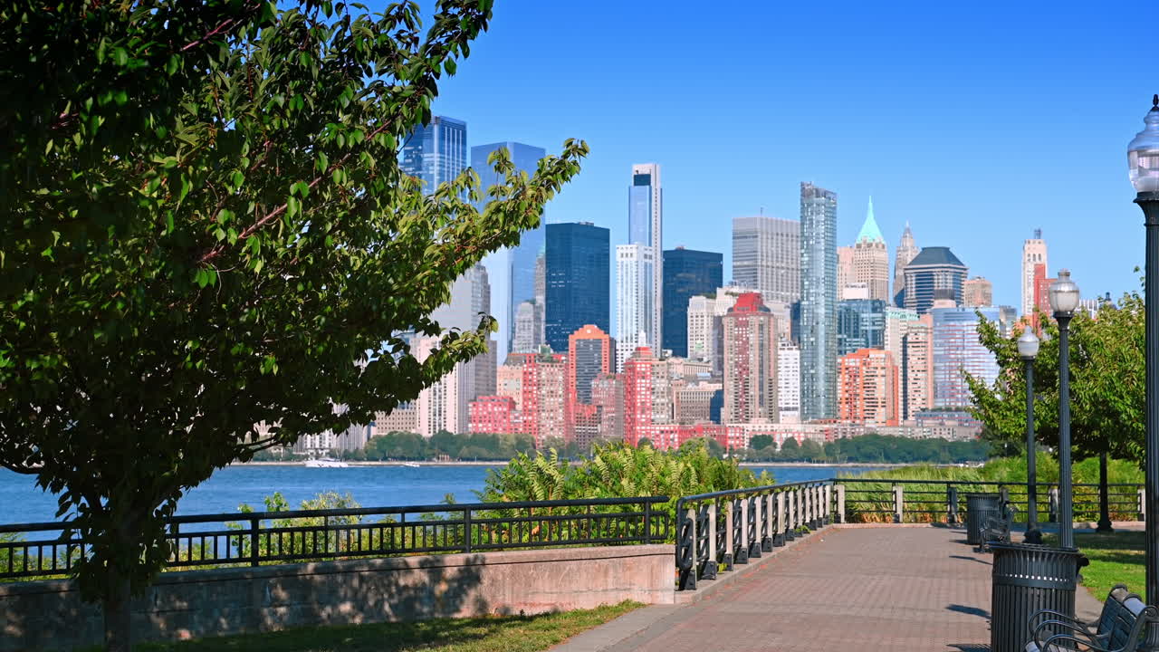 Calçadão no parque com vista para Jersey City e Manhattan. Um calçadão tranquilo em Jersey City, com bancos e luminárias com vista para o horizonte de Manhattan