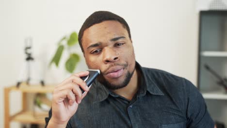 lindo hombre africano afeitándose con una afeitadora