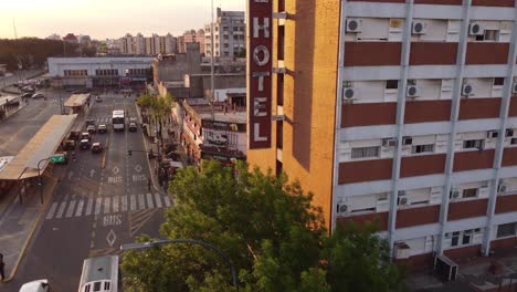 Toma-Aérea-Del-Antiguo-Hotel-Vintage-En-Buenos-Aires-Al-Lado-De-La-Estación-De-Autobuses-Y-El-Tráfico-En-La-Carretera-Durante-La-Puesta-De-Sol-En-Buenos-Aires