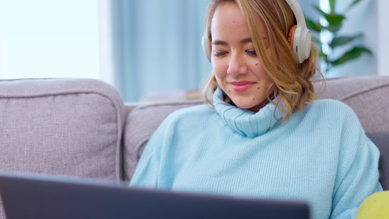 portátil, auriculares y mujer asiática en el sofá
