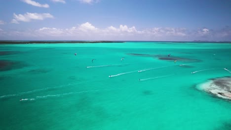 multiple kite surfers over the turquoise waters and sandbars of los roques, aerial view