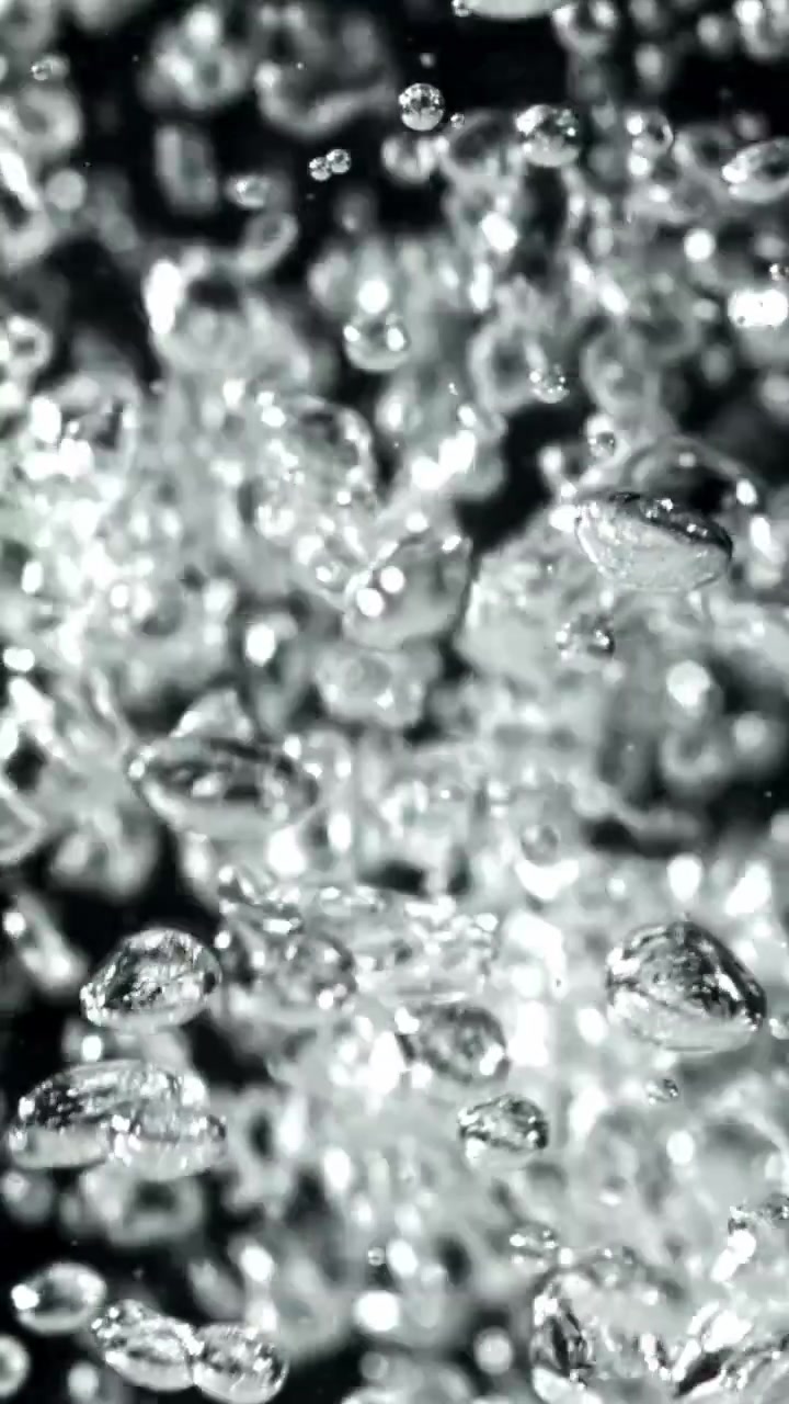 Bolle limpide e scintillanti che salgono nell'acqua su sfondo scuro