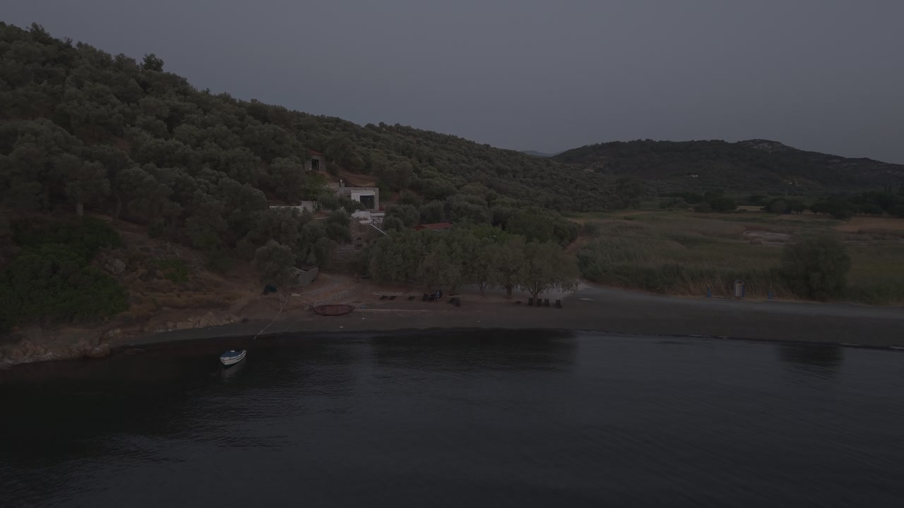 Aerial drone forward shot towards beach with wooden hammocks and boats at sunrise in Lesbos, Greece, calm sea 4K.
Aerial drone forward shot flying towards a beach with wooden hammocks and boats at sun