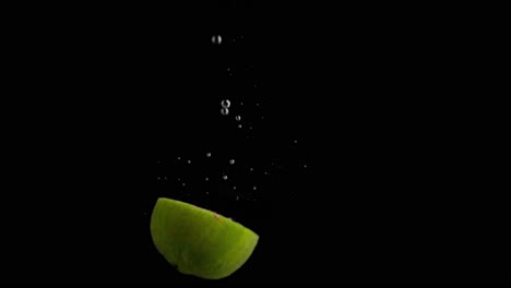 Lime-Falling-into-Water-Super-Slowmotion,-Black-Background,-lots-of-Air-Bubbles,-4k240fps