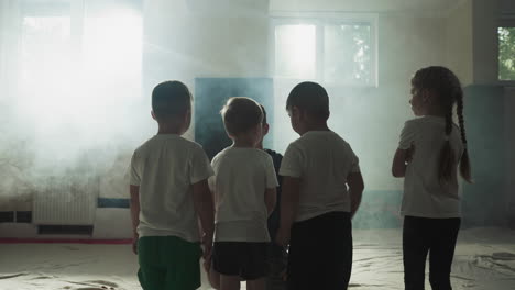 children listen to trainer in martial arts club. little fighting students with careful instructor prepare for exercising in gym slow motion. kids group