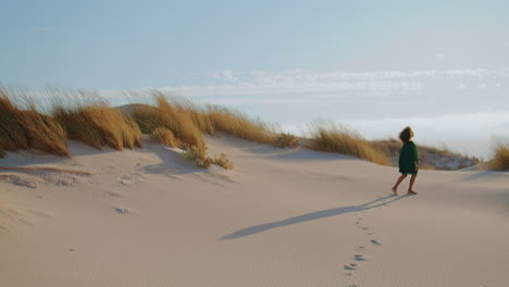 unknown girl walking desert leaving footprints on sand. woman stepping on dunes.