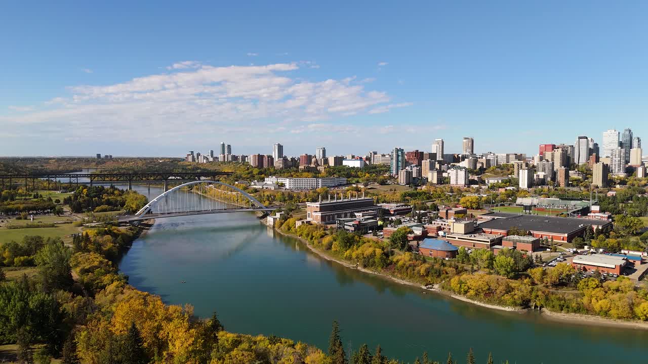 Ascending above trees in autumn revealing downtown Edmonton City