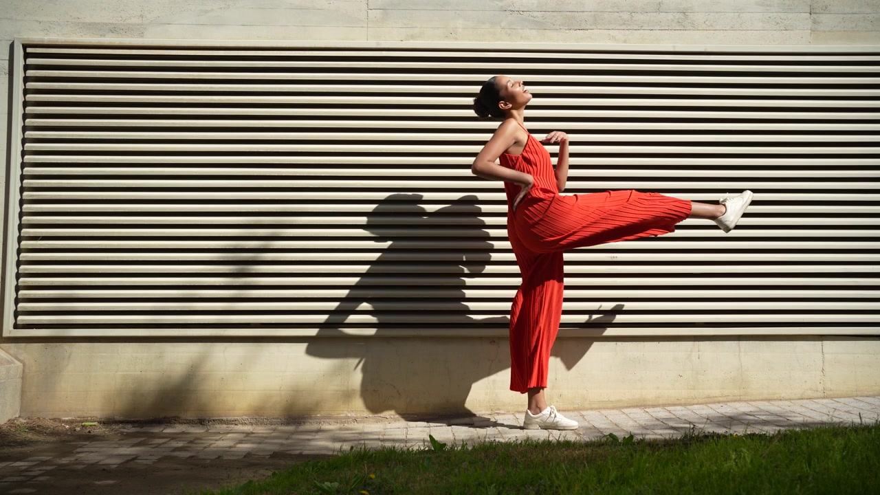Ein modisches Model, gekleidet in einem stilvollen roten Jumpsuit, posiert vor einem modernen Hintergrund.