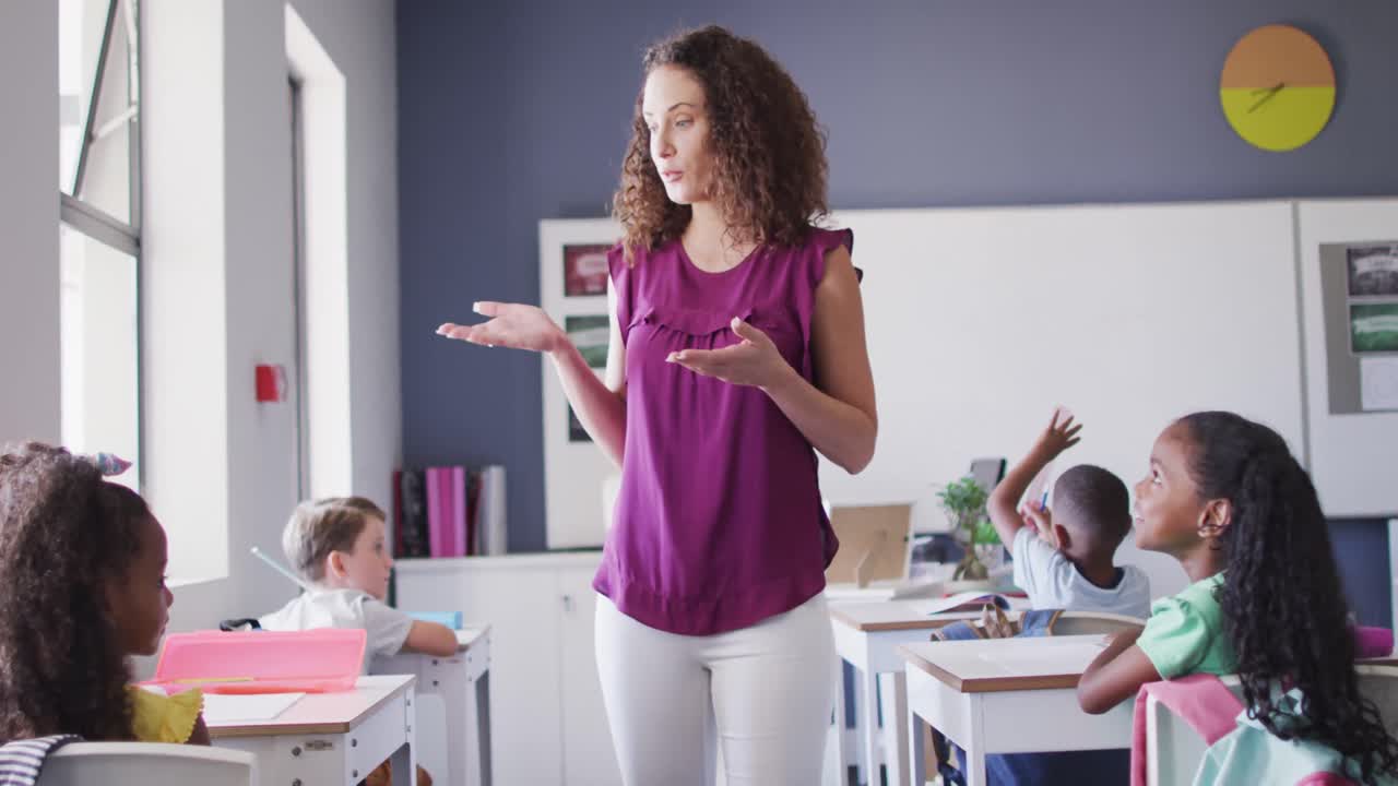 video de una maestra de escuela caucásica y niños de escuelas diversas estudiando en el aula