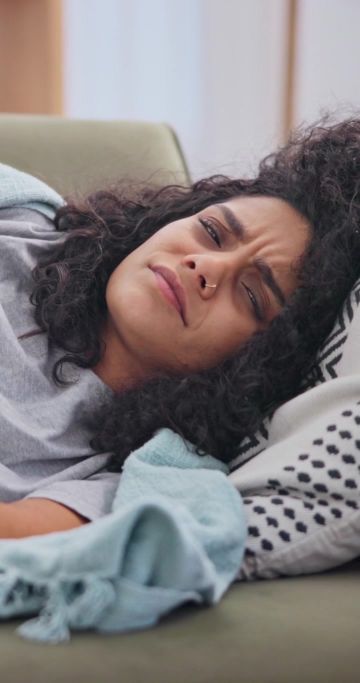 Young Woman Resting on Sofa Feeling Unwell
