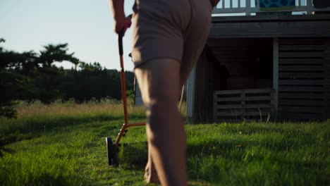 hombre recortando el césped manualmente con una cortadora de carretes. estática