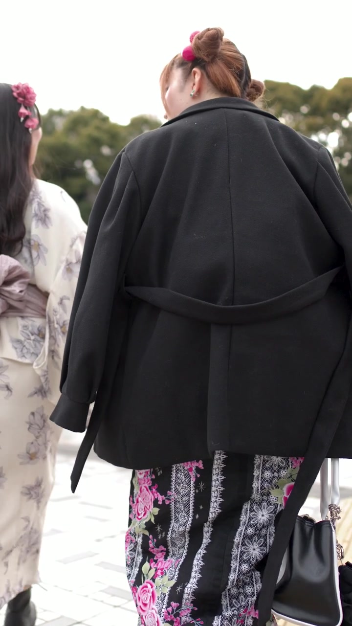 Geleneksel kimono ve siyah palto giymiş bir kadının dışarıda yürürken arkadan görünümü