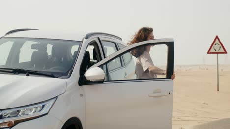 woman beside a white car in the desert