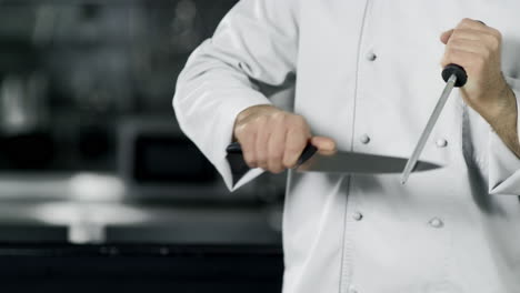 las manos del chef afilando el cuchillo en cámara lenta