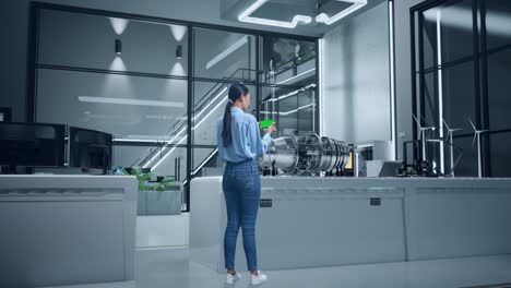 woman inspecting a jet engine using a green screen smartphone in a modern office-like factory environment