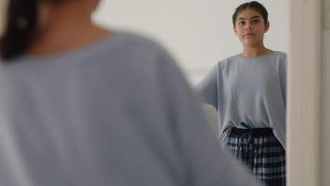 happy teenage girl practicing ballet dancing in bedroom looking in mirror rehearsing having fun dance on weekend morning wearing pajamas