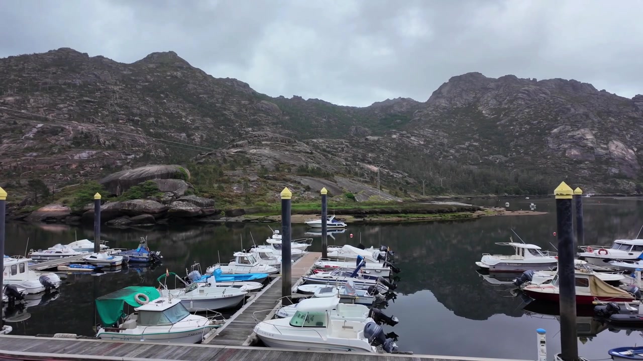 Piccolo porto turistico con barche ormeggiate a moli di legno a Dumbría, Spagna