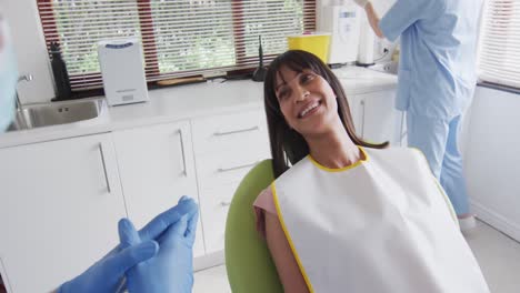 Dentista-Masculino-Caucásico-Con-Mascarilla-Preparando-A-Una-Paciente-Sonriente-En-Una-Clínica-Dental-Moderna