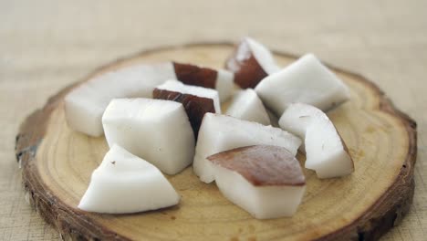 closeup of chopped coconut pieces on a wooden cutting board