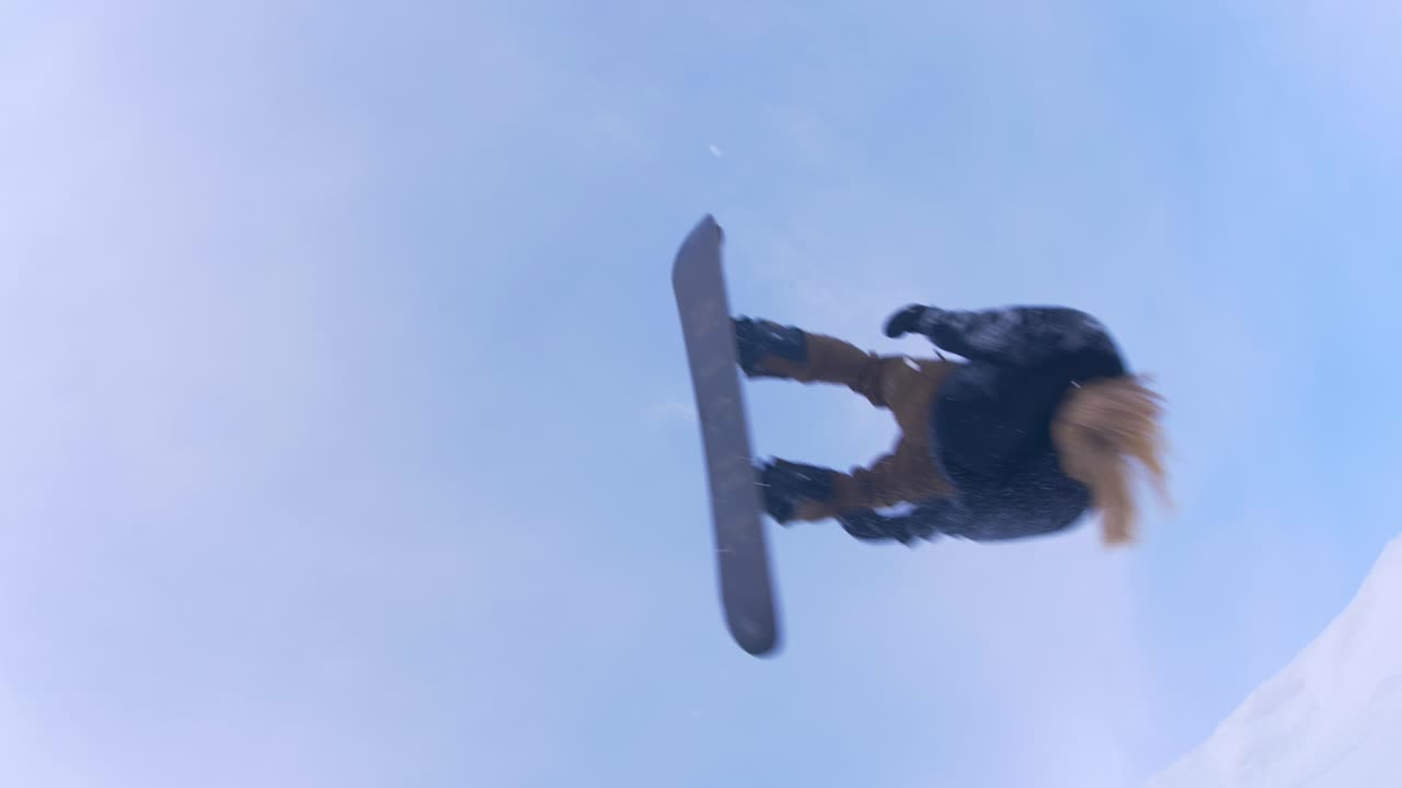 snowboarder en cámara lenta dando volteretas sobre la cámara mirando hacia arriba