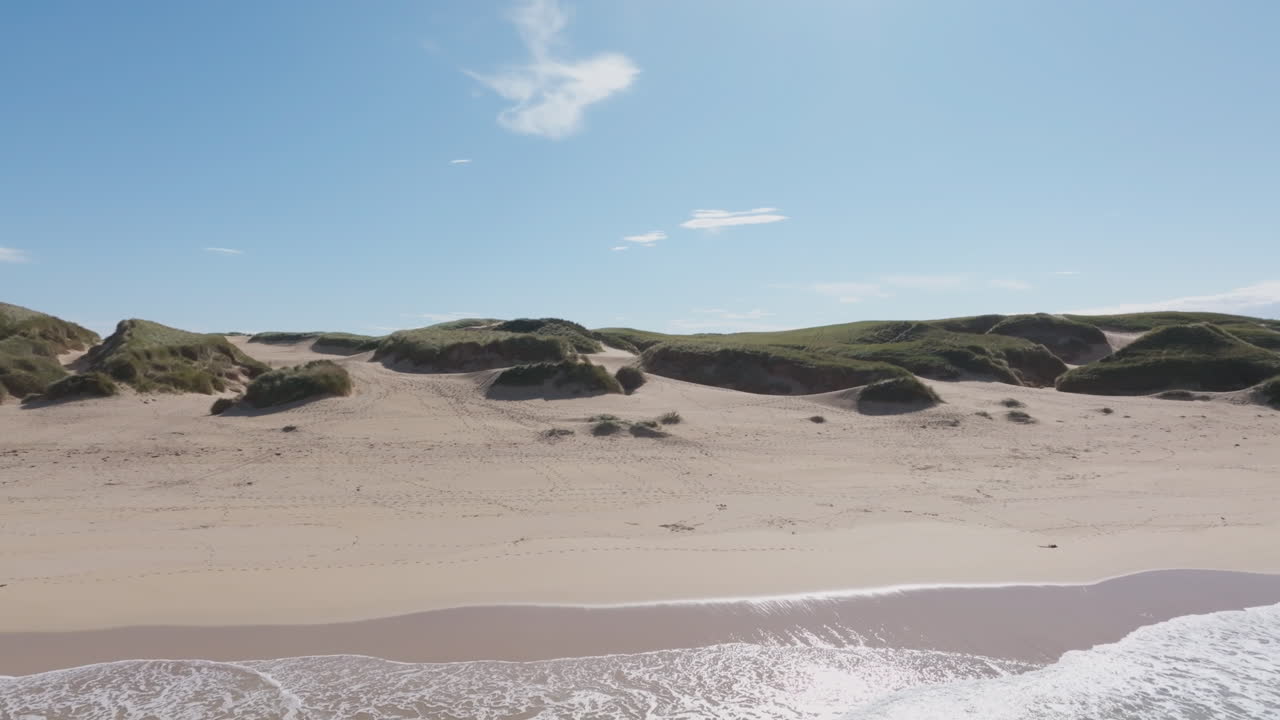Drone view over the dunes of Eoropie Beach on the Isle of Lewis, Outer Hebrides. Gentle Atlantic waves meet golden sand and bright blue skies along Scotland’s remote northern coast