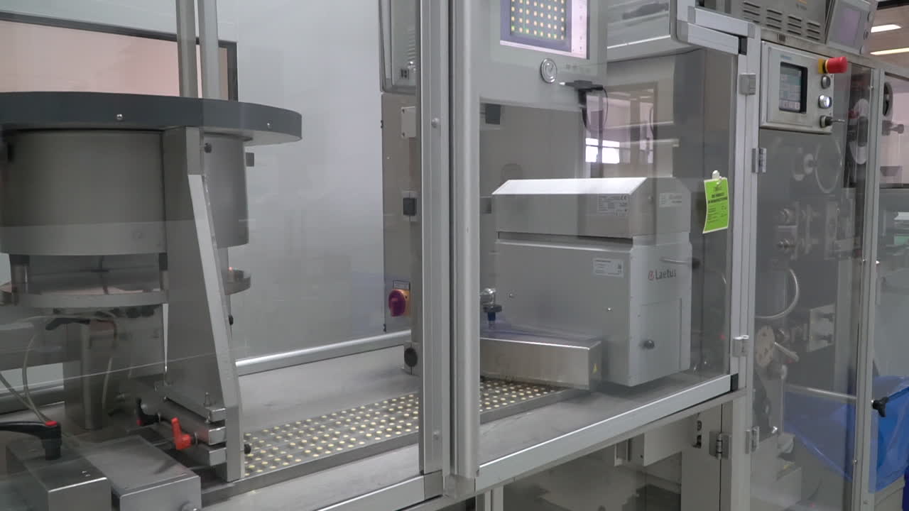 Steel conveyor belt of round drug pills in plastic reams in pharma lab, dolly