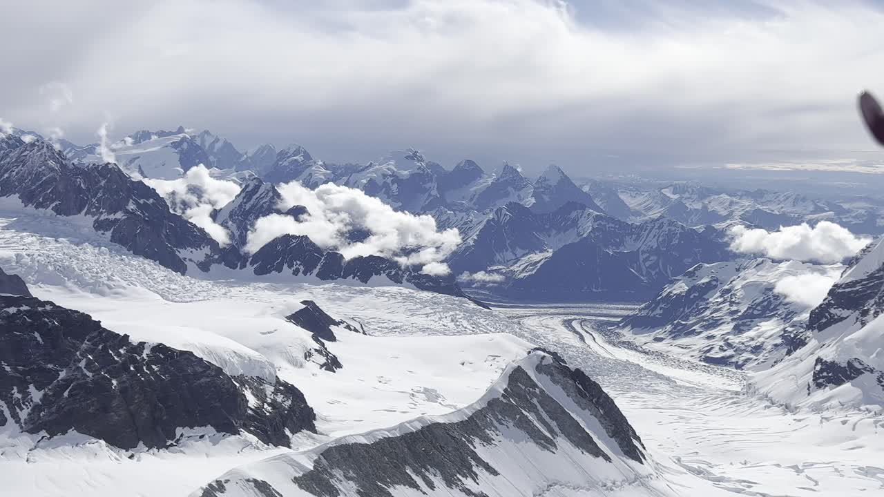 A stunning view of an airplane flying high above the Antarctica Himalayas. The aircraft moves over endless frozen peaks and deep icy valleys