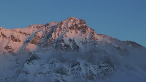 Experience-the-beauty-of-sunrise-over-a-snow-capped-mountain-range-silhouette-through-this-captivating-drone-footage