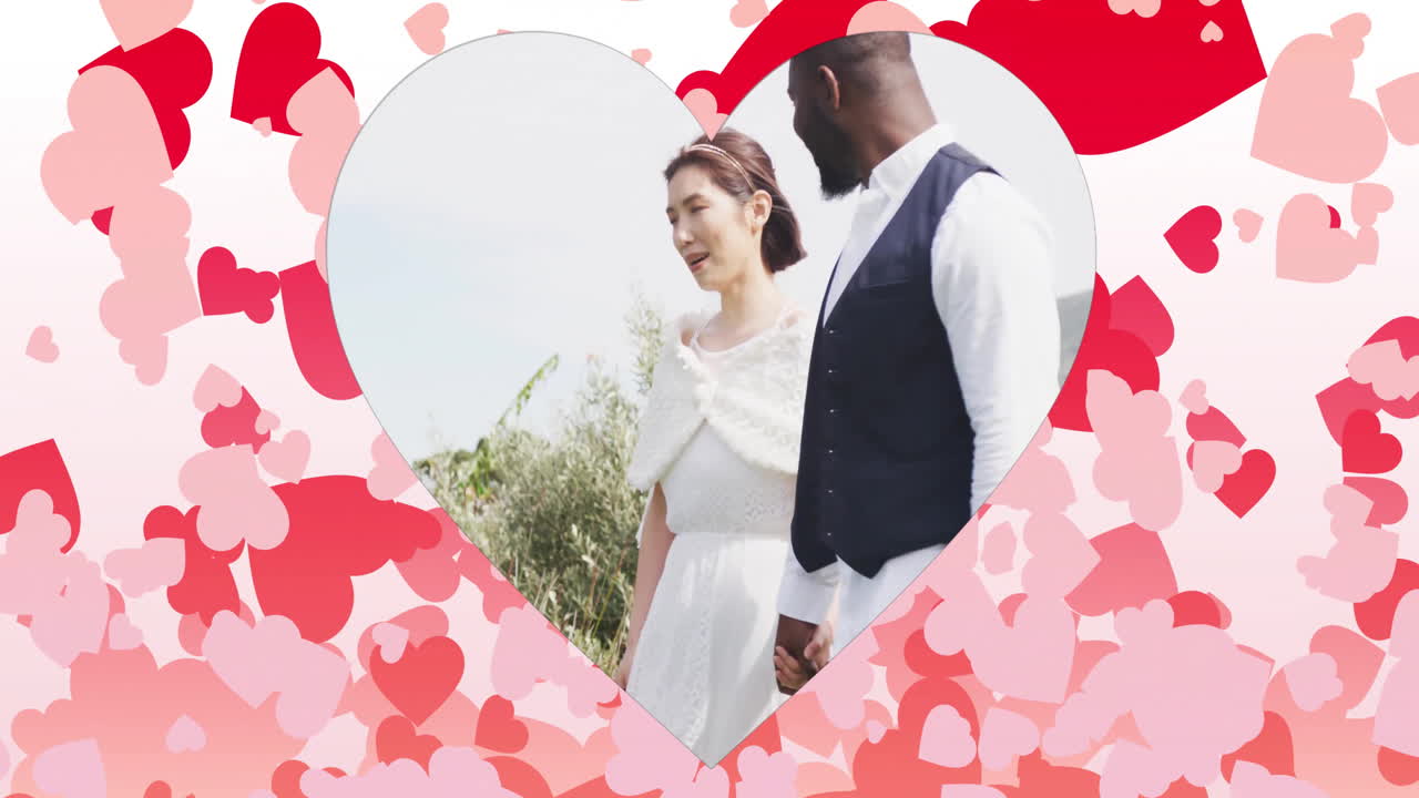 Heart-shaped frame with couple holding hands over pink and red hearts animation
