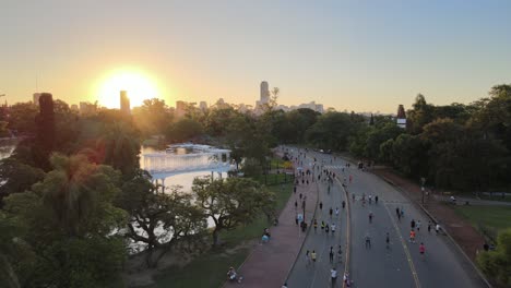 aerial dolly out of people in palermo woods pedestrian street near rosedal gardens at sunset, buenos aires