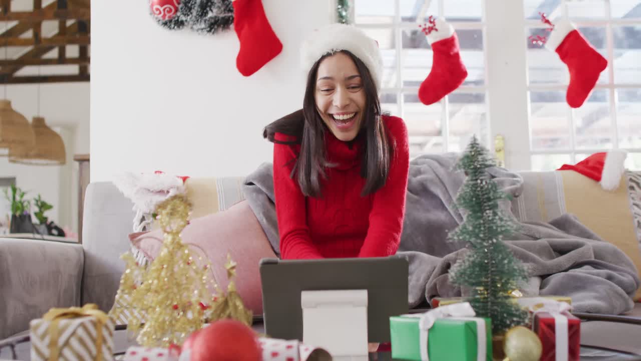 mujer biracial con sombrero de santa haciendo una videollamada