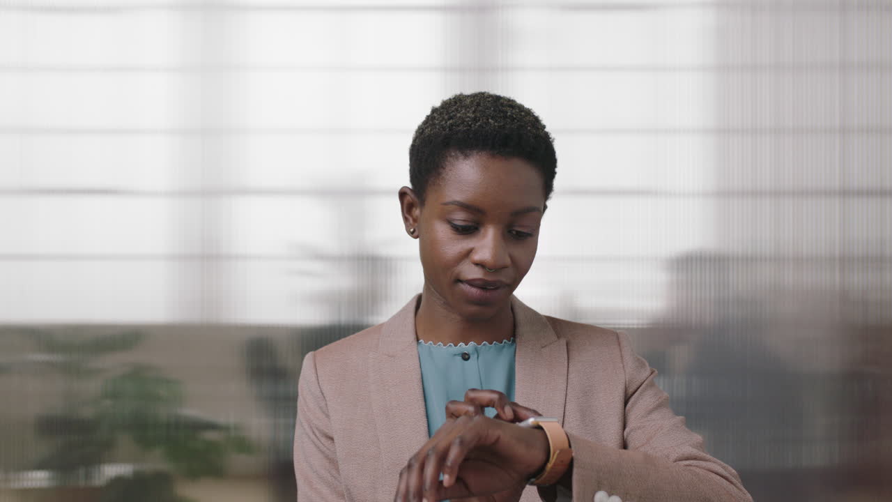 portrait of successful african american business woman checking messages using smart watch mobile technology black independent female working in office background