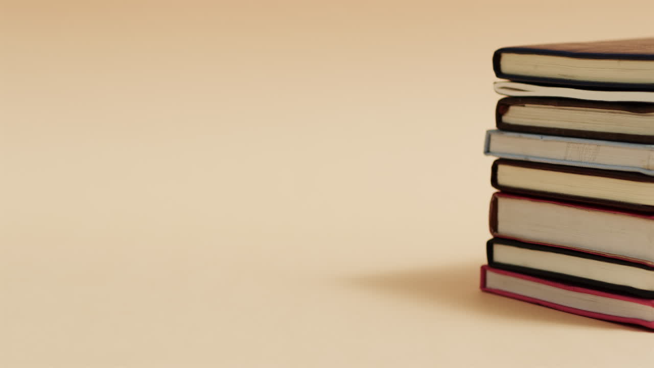 Close up of stack of books with copy space on beige background, in slow motion