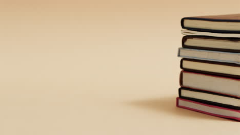 primer plano de una pila de libros con espacio de copia en un fondo beige, en cámara lenta