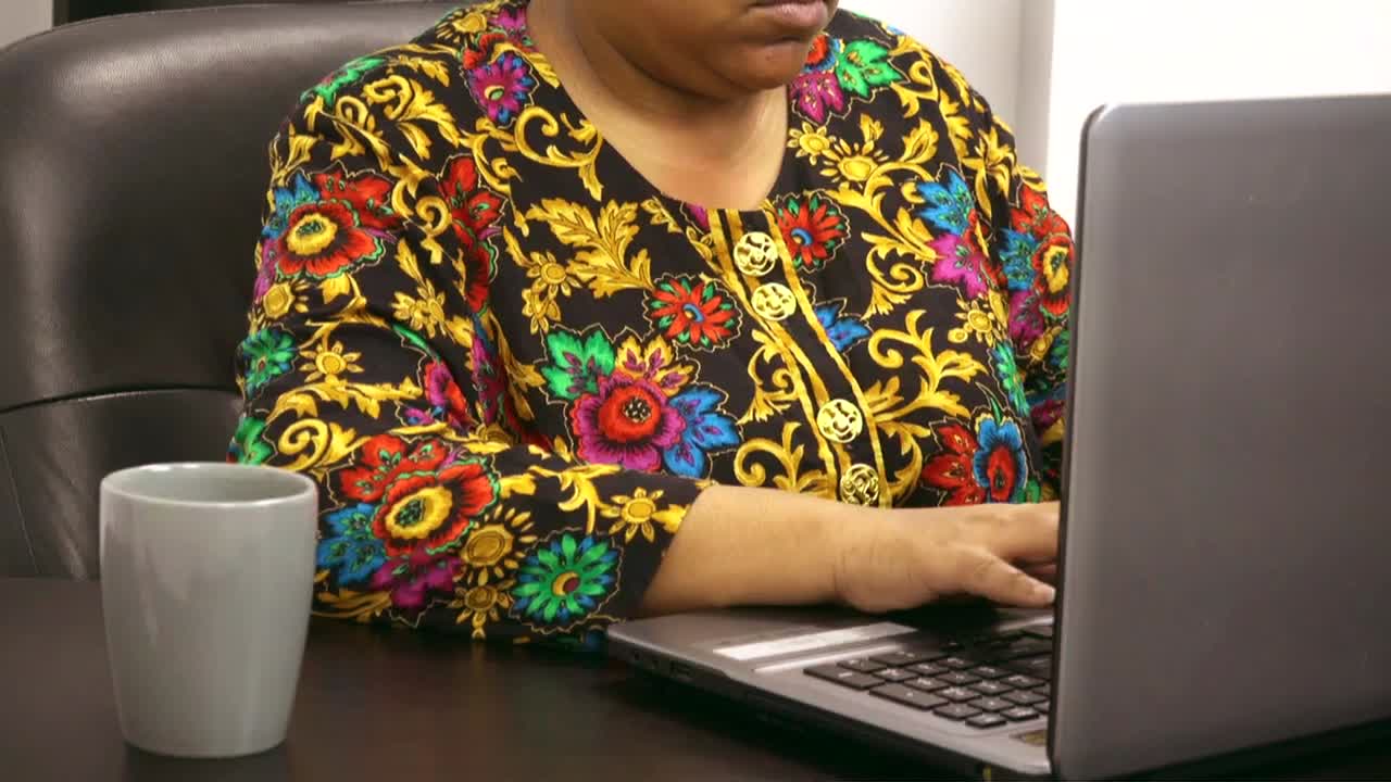 Black woman No face shown typing on computer in business setting
