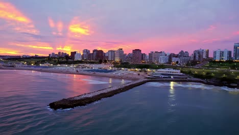 órbita aérea del rompeolas y la playa de playa grande en mar del plata, fondo al atardecer