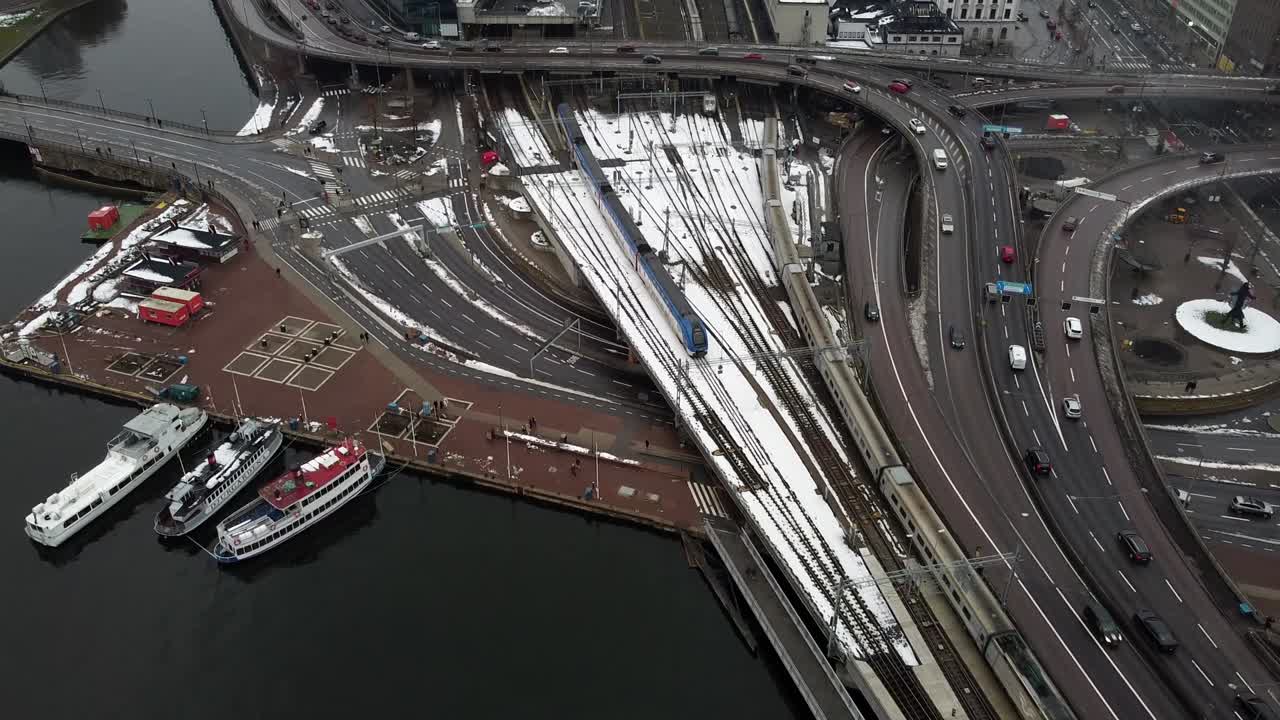 통근 열차 가 눈 이  ⁇ 인 철도 선로 를 가로질러 스 ⁇ 홀름 스웨덴 교통 센터 에 들어와 나간다