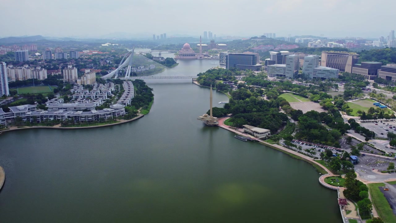 Kinematyczne ujęcie z drona z efektem slidera prezentujące panoramę nabrzeża Putrajaya z widocznym Mostem Seri Wawasan, Meczetem Putra i Pomnikiem Milenijnym